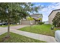 Beautiful landscaped front yard with green grass and trees surrounding the home with a two-car garage at 11871 Crestridge Loop, Trinity, FL 34655