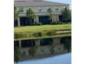 Relaxing backyard view with a serene pond reflecting the two-story home and lush green landscaping at 12952 Utopia Gardens Way, Riverview, FL 33579