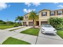 A townhome with brown shutters, a garage and a well manicured green lawn with palm trees at 12952 Utopia Gardens Way, Riverview, FL 33579