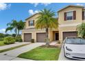 A townhome with brown shutters, a garage and a well manicured green lawn with palm trees at 12952 Utopia Gardens Way, Riverview, FL 33579