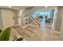 Bright foyer featuring wood-look floors, a staircase with a glass railing, and views into the living area at 1390 Gulf Blvd # Ph-5, Clearwater, FL 33767