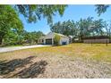 Wide angle shot of a well-maintained property featuring lush grass, mature trees, and a convenient two-car garage at 18902 Spring Hollow Dr, Lutz, FL 33559