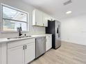 Bright kitchen featuring white cabinets, stainless steel appliances, subway tile, and wood grain floors at 200 Lewis Se Blvd, St Petersburg, FL 33705
