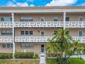 Close-up exterior showing balcony with light beige exterior, stairs, small palm tree, and manicured landscaping at 2436 Rhodesian Dr # 24, Clearwater, FL 33763