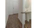 A bathroom featuring wood-look floors, a pedestal sink, and white walls for a clean and bright ambiance at 34847 Daisy Meadow Loop, Zephyrhills, FL 33541