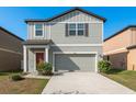 Charming two-story home featuring a gray facade, attached garage and well-maintained landscaping at 34855 Daisy Meadow Loop, Zephyrhills, FL 33541