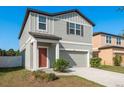 Charming two-story home featuring a gray facade, attached garage and well-maintained landscaping at 34855 Daisy Meadow Loop, Zephyrhills, FL 33541