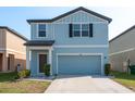 Charming two-story home featuring blue siding, a well-manicured lawn, and an attached garage at 34866 Daisy Meadow Loop, Zephyrhills, FL 33541