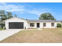 Charming single-story home with a modern white exterior, black trim and garage door, and a well-manicured lawn at 3707 Orangepointe Rd, Valrico, FL 33596