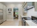 Modern kitchen featuring stainless steel appliances, gray cabinetry, stylish backsplash, and wood look floors at 4101 Brooke Dr, Valrico, FL 33594