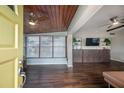Open-concept living room featuring hardwood floors, a wood ceiling, and a bright sunroom at 7108 N Howard Ave, Tampa, FL 33604
