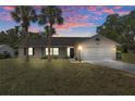 Exterior of a charming single-story home at dusk with lush lawn and two palm trees at 7337 Glasgow Rd, Weeki Wachee, FL 34613