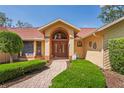 Inviting front entrance with a brick walkway, arched doorway, and well-manicured landscaping at 7353 Dogwood Cres, Spring Hill, FL 34607