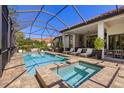 Relaxing outdoor pool area featuring a screened-in pool, spa, and covered patio with lounge seating at 8434 Dunham Station Dr, Tampa, FL 33647