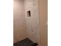 Bright white shower with black tiled floor and corner shelf, accented by natural light at 10116 N Highland Ave, Tampa, FL 33612