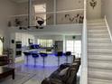 Open-concept living area with high ceilings, tile floors, a modern kitchen, and stairs leading to the second floor at 11727 Spanish Lake Dr, Tampa, FL 33635