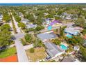 Aerial view of a home with a screened-in patio and pool, surrounded by mature trees and lush landscaping in a quiet neighborhood at 1501 Wisconsin Ave, Palm Harbor, FL 34683
