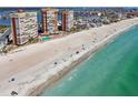 Wide sandy beach aerial view with ocean waves, condominium buildings, pool, and blue skies in this coastal community at 17920 Gulf Blvd # 1302, Redington Shores, FL 33708