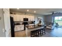 Open-concept kitchen flowing into a living area, featuring white cabinets and a center island at 1853 Hovenweep Rd, Wesley Chapel, FL 33543