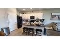 Modern kitchen with white cabinets, black appliances, and a granite-topped island with bar stool seating at 1853 Hovenweep Rd, Wesley Chapel, FL 33543