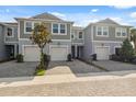 Charming townhome with gray siding, a one-car garage, and a well-maintained paver driveway under a blue sky at 2529 Arbor Wind Dr, Lutz, FL 33558
