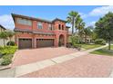 Mediterranean-style home featuring a brick driveway, two-car garage, and well-manicured landscaping at 2608 Calvano Dr, Land O Lakes, FL 34639