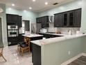 Modern kitchen boasts stainless steel appliances, dark cabinets, white quartz countertops, and a stylish island with seating at 29042 Rivergate Run, Wesley Chapel, FL 33543