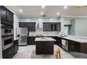 Modern kitchen boasts stainless steel appliances, dark cabinets, white quartz countertops, and a stylish island with seating at 29042 Rivergate Run, Wesley Chapel, FL 33543