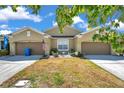 Charming exterior of tan home with well-manicured lawn and garden decorations and blue skies at 30327 Lettingwell Cir, Wesley Chapel, FL 33543