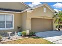 Home featuring a brown garage door, a bird bath, lawn decorations, and a sunny sky at 30327 Lettingwell Cir, Wesley Chapel, FL 33543