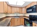 A kitchen featuring wooden cabinets, granite countertops, a stainless steel sink, and black appliances at 4900 Brittany S Dr # 1810, St Petersburg, FL 33715
