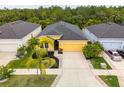 Aerial view of a yellow single-Gathering home with a two-car garage and lush, mature landscaping at 5048 Inshore Landing Dr, Apollo Beach, FL 33572