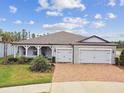 Charming single-story home featuring a brick driveway, two-car garage and beautifully landscaped front yard under a sunny sky at 5670 Shorebird Br, Land O Lakes, FL 34638