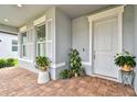 Inviting front porch with brick flooring, white door and trim, plus lush greenery and potted plants on display at 5670 Shorebird Br, Land O Lakes, FL 34638