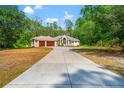 Stately one story home with a long driveway and two-car garage surrounded by lush trees at 7340 West Dr, Wesley Chapel, FL 33544