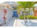 Inviting entryway with blue double doors, white stone landscaping, and tropical plants at 7657 Nottinghill Sky Dr, Apollo Beach, FL 33572