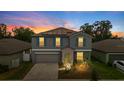 Twilight view of a charming two-story home with grey siding, teal shutters, and a two-car garage at 13380 Great Plains Dr, Riverview, FL 33579