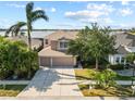 Aerial shot featuring the home, manicured lawn, landscaping, driveway, and partial lake view at 1858 Mira Lago Cir, Ruskin, FL 33570