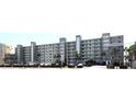 Multi-story condo building with a parking lot in front and palm trees, offering convenient and beachfront living at 18650 Gulf Blvd # 203, Indian Shores, FL 33785