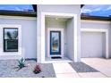 Inviting front entrance with a decorative glass door, modern landscaping, and a well-lit porch at 18657 Obregan Dr, Spring Hill, FL 34610