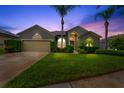 Inviting home at twilight featuring professional landscaping, mature palm trees, and a well-manicured lawn at 2808 Abbey Grove Dr, Valrico, FL 33594