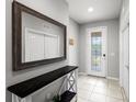 Bright foyer with tile flooring, console table, large mirror and decorative front door with sidelights at 5014 Fallen Leaf Dr, Riverview, FL 33578