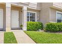 Close-up of a townhome's entrance featuring a well-maintained lawn and manicured shrubbery at 732 Kensington Lake Cir, Brandon, FL 33511