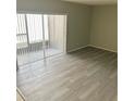 Living room with wood-look flooring and sliding glass door for natural light and access to balcony at 7506 Presley Pl # 107, Tampa, FL 33617