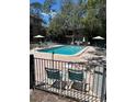 Community pool surrounded by lounge chairs and greenery, fenced in for safety and privacy at 7506 Presley Pl # 107, Tampa, FL 33617