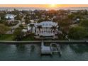 Sunset aerial view of a grand waterfront estate featuring a private dock and swimming pool at 755 Bay Esplanade, Clearwater Beach, FL 33767