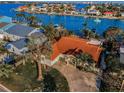 Aerial shot of a single-story home featuring a red tile roof, circular driveway, and lush landscaping with palm trees at 795 116Th Ave, Treasure Island, FL 33706