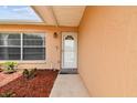 Inviting front entrance featuring a white door, a sidelight window, and lush mulch landscaping at 8531 Woodcrest Dr, Port Richey, FL 34668