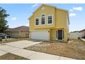 Bright yellow two-story home with a two car garage, black door, and well-maintained lawn at 11323 Ivy Flower Loop, Riverview, FL 33578