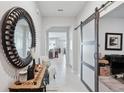 Elegant entryway with tile flooring, decorative mirror, barn door, and neutral paint at 13055 Willow Grove Dr, Riverview, FL 33579